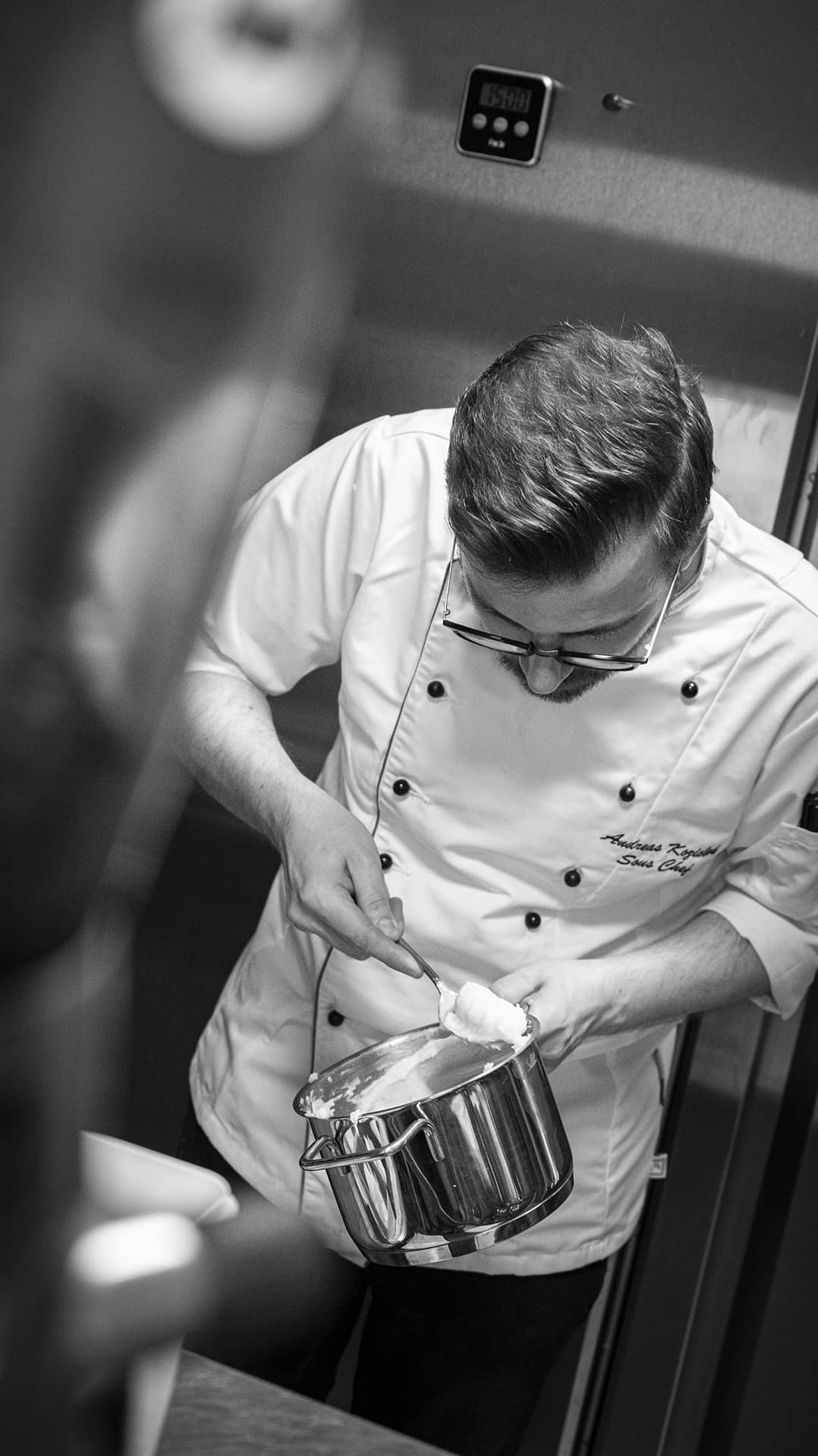 Sous-Chef holt kartoffelpürre mit Löffel aus einem Topf