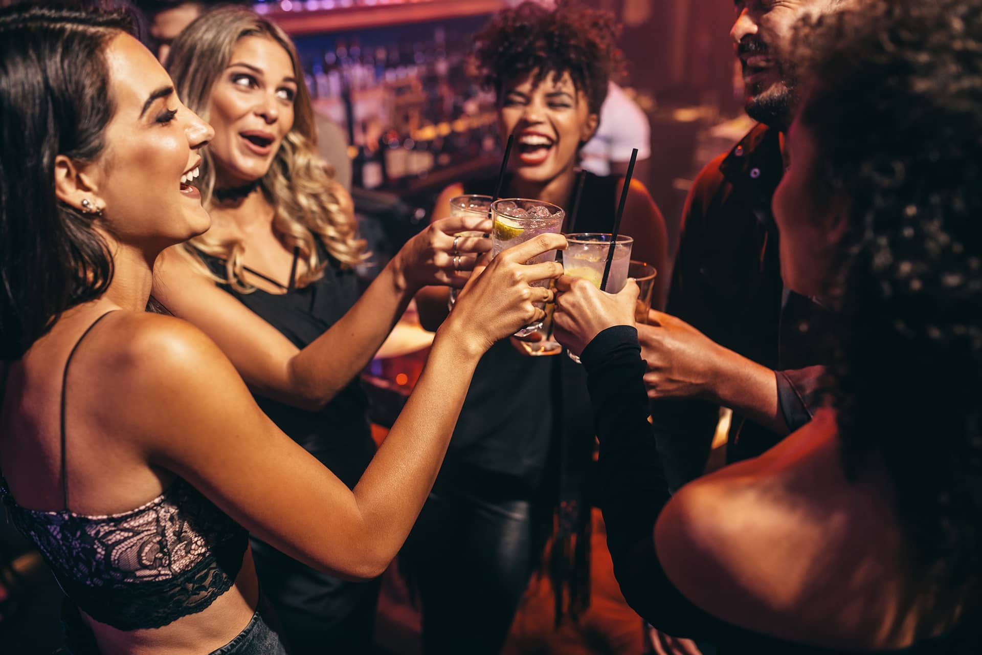 Junge Menschen im Club stoßen mit Getränken an